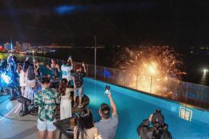 a group of people standing around a swimming pool with fireworks at The Atier Gem Suites in Nha Trang