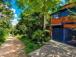a house with a blue gate next to a dirt road at Bosque da Lua - Suite with 2 bathrooms - Up to 5 guests in Itupeva