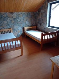 two beds in a room with a stone wall at Kompleks Gurman in Pʼklište +8 photos