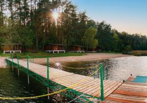a dock on a lake with a cabin in the background at Domki Dębrzyno in Juszki