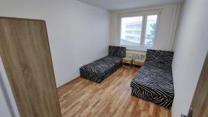 a room with two beds and a chair and a window at Apartmán pro 6 osob, Most M2 in Most