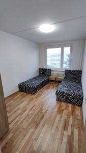 two beds in a room with a wooden floor at Apartmán pro 6 osob, Most M2 in Most