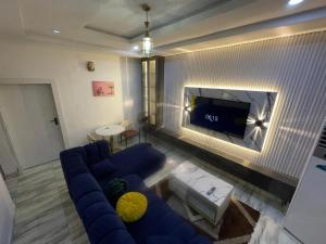 a living room with a blue couch and a tv at Otunbas Crib Apartment in Gbogije