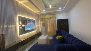 a living room with a blue couch and a tv at Otunbas Crib Apartment in Gbogije +6 photos
