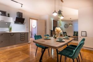 a kitchen and dining room with a wooden table and green chairs at Aurea Lika - Gospic in Gospić +27 photos