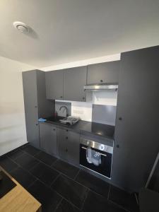 a kitchen with gray cabinets and a black tile floor at Maison convivial in Vireux-Wallerand