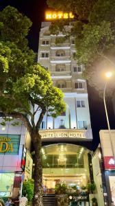 a tall white hotel with a tree in front of it at White Lion Hotel in Ho Chi Minh City +36 photos