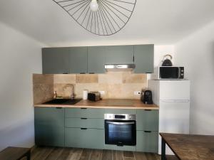 a kitchen with green cabinets and a sink and a refrigerator at Une escapade en Provence in Pertuis