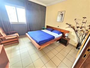 a bedroom with a bed with blue sheets and a chair at The Yafé Bastos 6 in Yaoundé