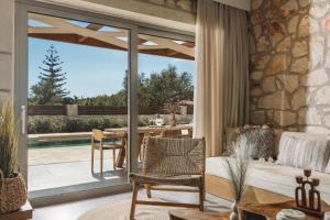 a living room with a couch and a table and a patio at Bedrock beachside villa with private pool in Vasilikos