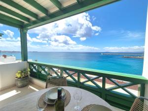 a table with wine glasses on a balcony overlooking the ocean at Casa Balcón del Puerto in Playa Blanca