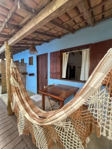 a room with a hammock and a table on a deck at Pousada Aratu - Vila de Caraíva - A apenas 100 metros da travessia de canoa in Caraíva