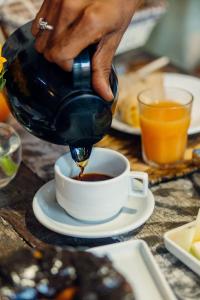 a person pouring coffee into a cup on a table at Pousada Aratu - Vila de Caraíva - A apenas 100 metros da travessia de canoa in Caraíva