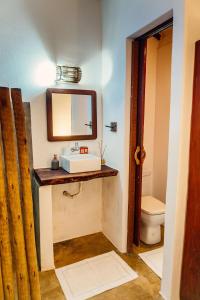 a bathroom with a sink and a mirror and a toilet at Pousada Aratu - Vila de Caraíva - A apenas 100 metros da travessia de canoa in Caraíva
