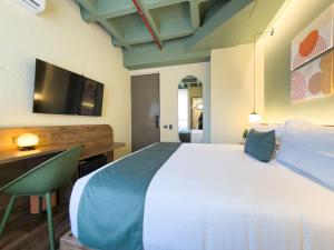 a bedroom with a bed and a desk and a tv at Urbit Garden Hotel in Medellín