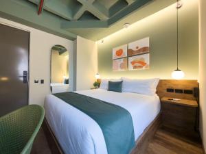 a bedroom with a large white bed and a chair at Urbit Garden Hotel in Medellín