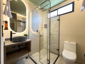 a bathroom with a toilet and a glass shower at Urbit Garden Hotel in Medellín