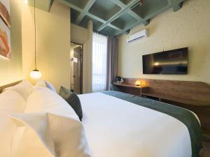 a bedroom with a white bed and a tv at Urbit Garden Hotel in Medellín