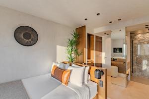 a bedroom with a white bed with a clock on the wall at Agnadema Apartments in Firostefani