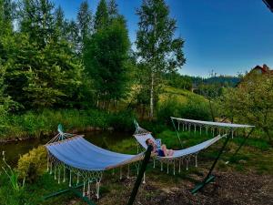 a person laying in a hammock next to a river at Stop Time in Slavske
