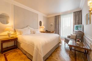 ein Hotelzimmer mit einem großen Bett und einem Stuhl in der Unterkunft Colombi Hotel in Freiburg im Breisgau + 54 Fotos