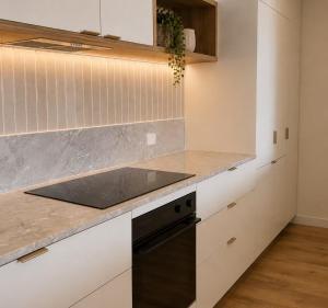 a kitchen with white cabinets and a black dishwasher at Lumi Residence Robina in Gold Coast