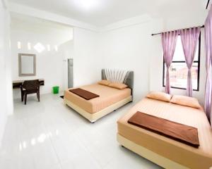 two beds in a room with a desk and a window at Lansogo Homestay in Painan