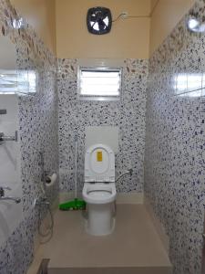 a bathroom with a toilet with a window and a clock at Mulaqat Homestay in Siliguri