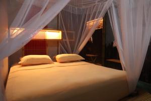 a bed with white sheets and pillows in a room at Bukit Lawang Lodge in Bukit Lawang