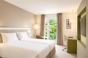 a hotel room with a large bed and a window at Best Western Plus Paris Meudon Ermitage in Meudon