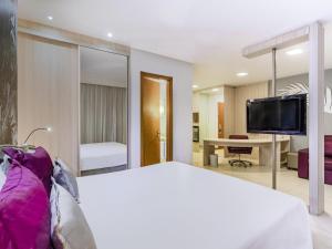 a hotel room with a bed and a tv at Mercure Salvador Boulevard Hotel in Salvador +46 photos