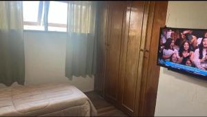 a bedroom with a flat screen tv on a wall at Quarto Meudon in Teresópolis