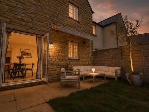 a patio with a couch and a table in front of a house at Silverstone Paddock Retreat in Silverstone