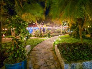 a garden at night with palm trees and lights at Xalli Beach Hotel in Altagracia