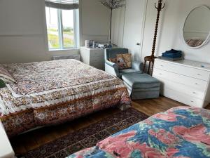a bedroom with two beds and a mirror and a chair at Couchers de soleil à Sainte-Flavie in Sainte-Flavie