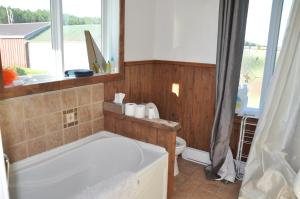 a bathroom with a tub and a toilet and a window at Couchers de soleil à Sainte-Flavie in Sainte-Flavie +15 photos