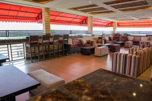 a restaurant with chairs and tables and a bar at Citistay Apartments in Abuja