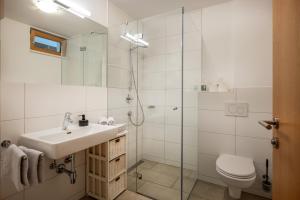 a white bathroom with a sink and a shower at Sonnplatzl Appartement Westendorf in Westendorf