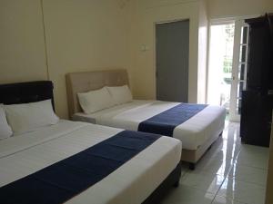 two beds sitting in a room with a window at Cozy Highland in Tanah Rata +24 photos