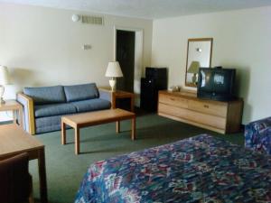 a hotel room with a bed and a couch and a television at Will Rogers Inn in Claremore