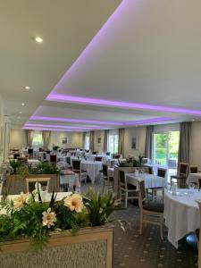 a restaurant with white tables and chairs and purple ceilings at Logis Hotel Restaurant de l'Abbaye in Ferrières
