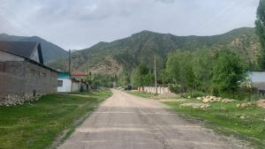 an empty dirt road with mountains in the background at House near the mountains in Karakol