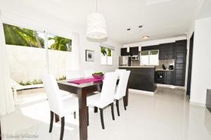 uma sala de jantar com uma mesa de madeira e cadeiras brancas em The Sanctuary @ Los Corales em Punta Cana