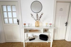 a white console table with a mirror on the wall at The Dutt's cocoon spacious and charming T3 in Duttlenheim