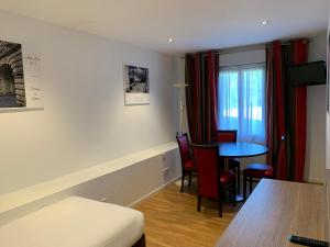 a room with a table and chairs and a room with a bed at Logis Hotel Restaurant de l'Abbaye in Ferrières