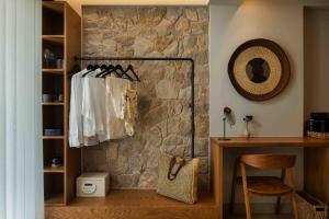 a room with a stone wall with clothes hanging on a rack at Kelyfos Nafpaktos in Nafpaktos +70 photos