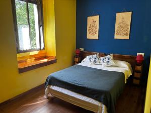 a bedroom with a bed with blue walls and a window at Apartamentos Dos Aguas in Aguasmestas