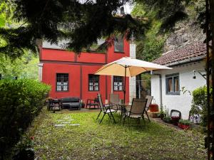 a patio with chairs and an umbrella in front of a red building at Apartamentos Dos Aguas in Aguasmestas