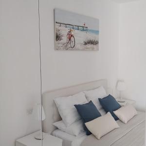 a white bedroom with a bed with blue pillows at B&B El Dorado in Lido di Pomposa