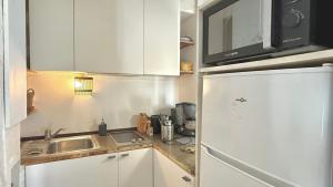 a kitchen with white cabinets and a refrigerator at Le Duplex in Denicé
